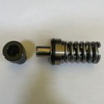 Metal compression damper with a coiled chrome spring and cylindrical plunger, laid beside a round end cap on a white background.